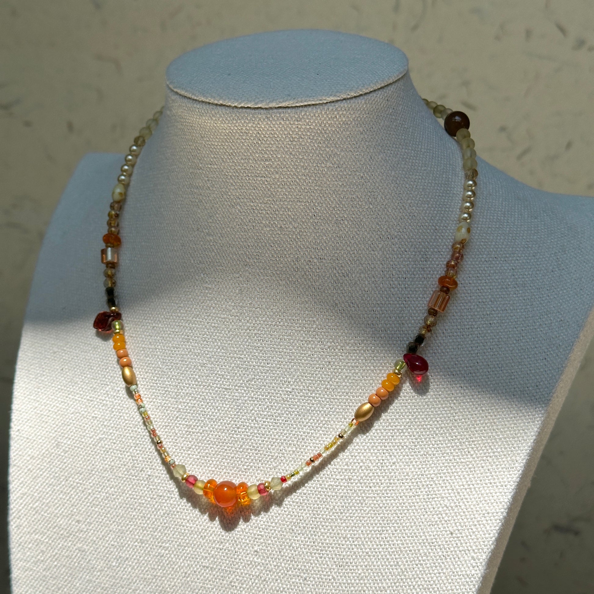 Golden Nectar Necklace worn on bust, showcasing honey-amber focal cluster and elegant gold-red balance
