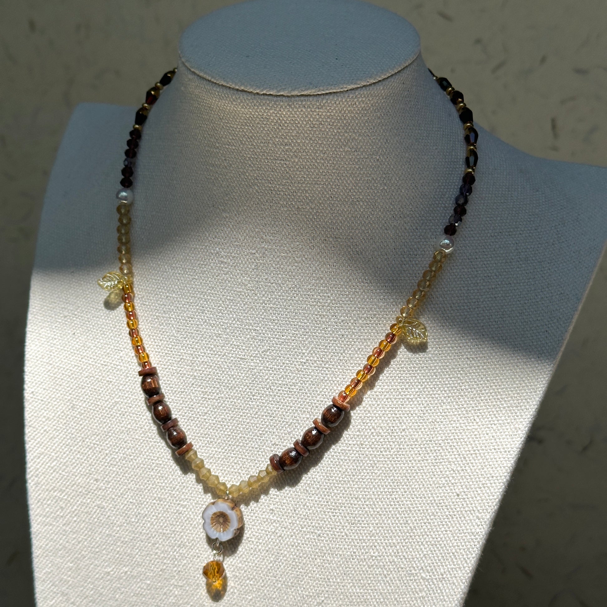 Amber Daisy Necklace worn on bust, showcasing ceramic daisy pendant, honey-amber beads, and elegant gold highlights
