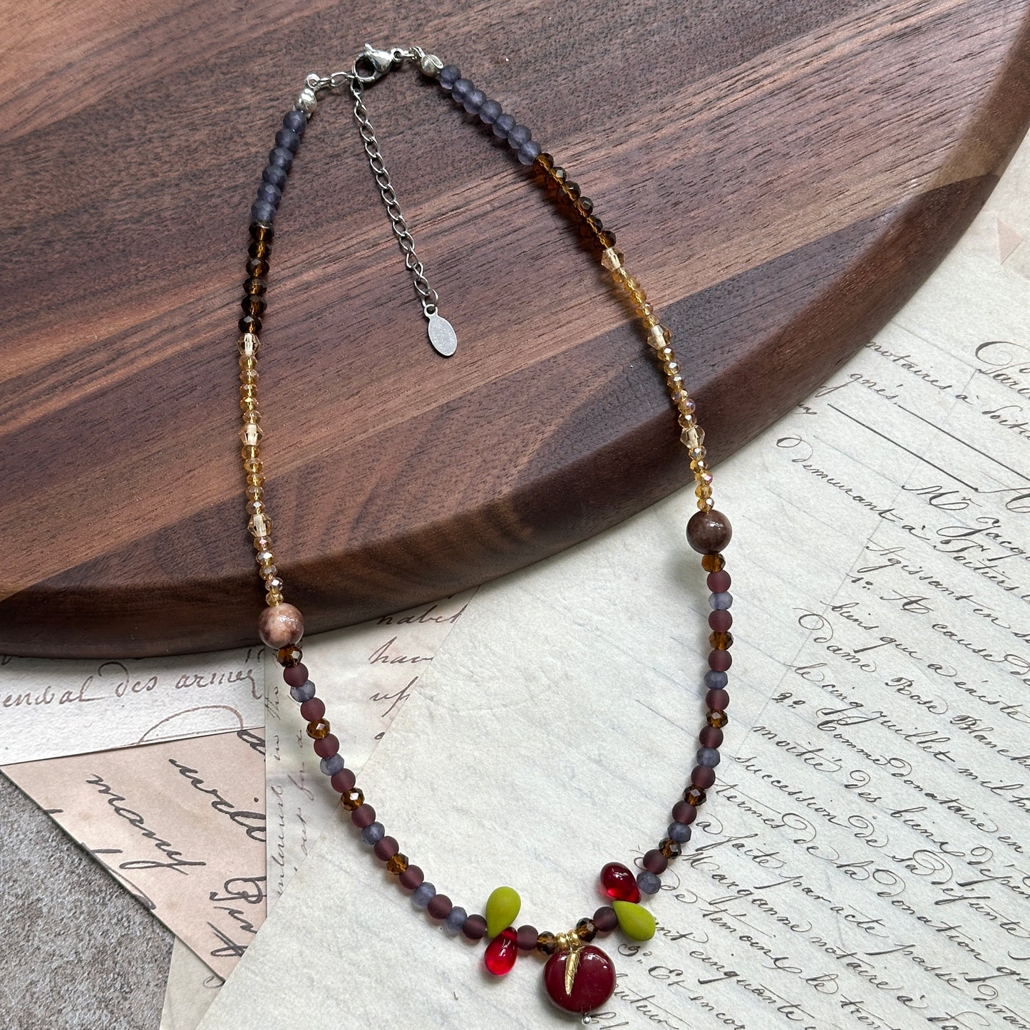 Close-up of glossy red apple glass bead with lime leaf accents