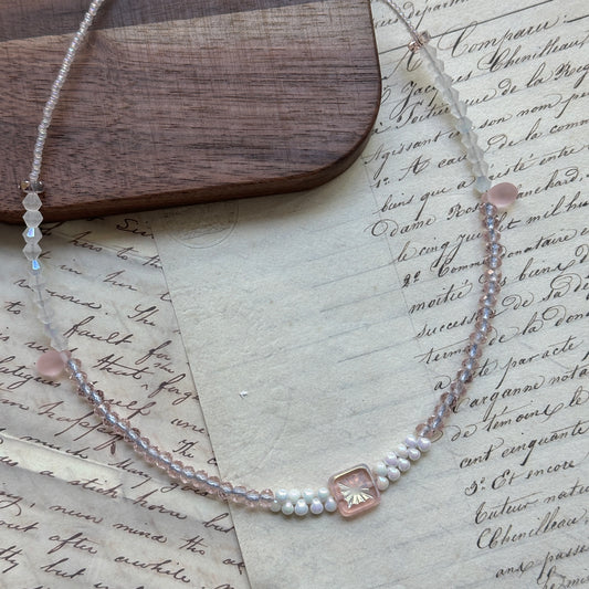 Blush Crystal Necklace close-up on rustic surface, featuring square bezel-set crystal centerpiece with blush pink and clear beads