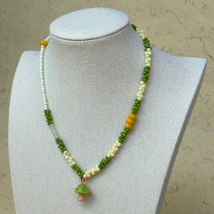 Forest Mushroom Necklace worn on bust, highlighting glass mushroom charm with lively green and ivory bead palette