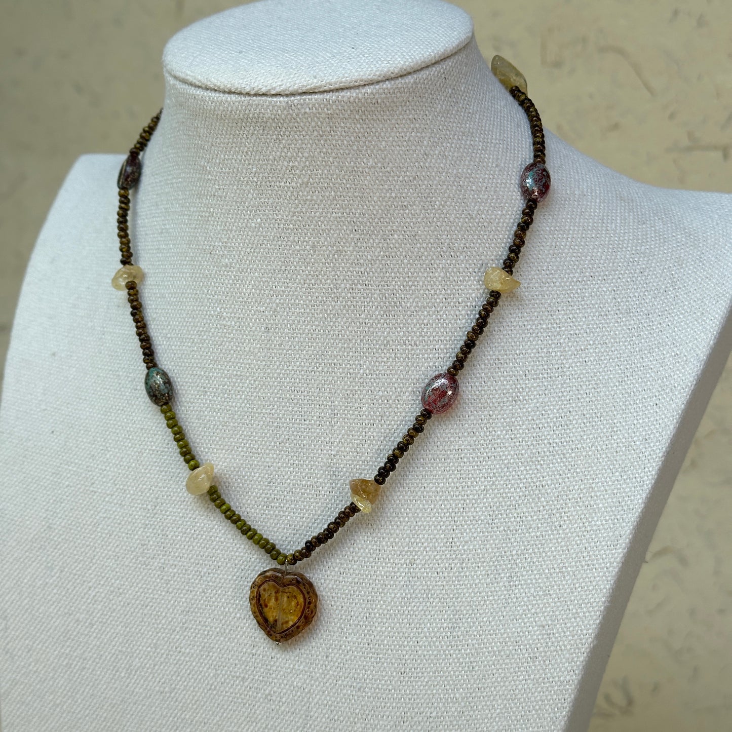 Aurora Heart Necklace worn on bust, showing romantic heart pendant with glowing gold details and colorful bead strand