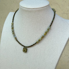Gilded Bloom Necklace worn on bust, showing elegant golden and dark bead strand with engraved square floral charm