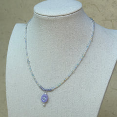 Aurora Dew Necklace displayed on bust, highlighting delicate beaded strand and glowing lavender pendant with crystal detail