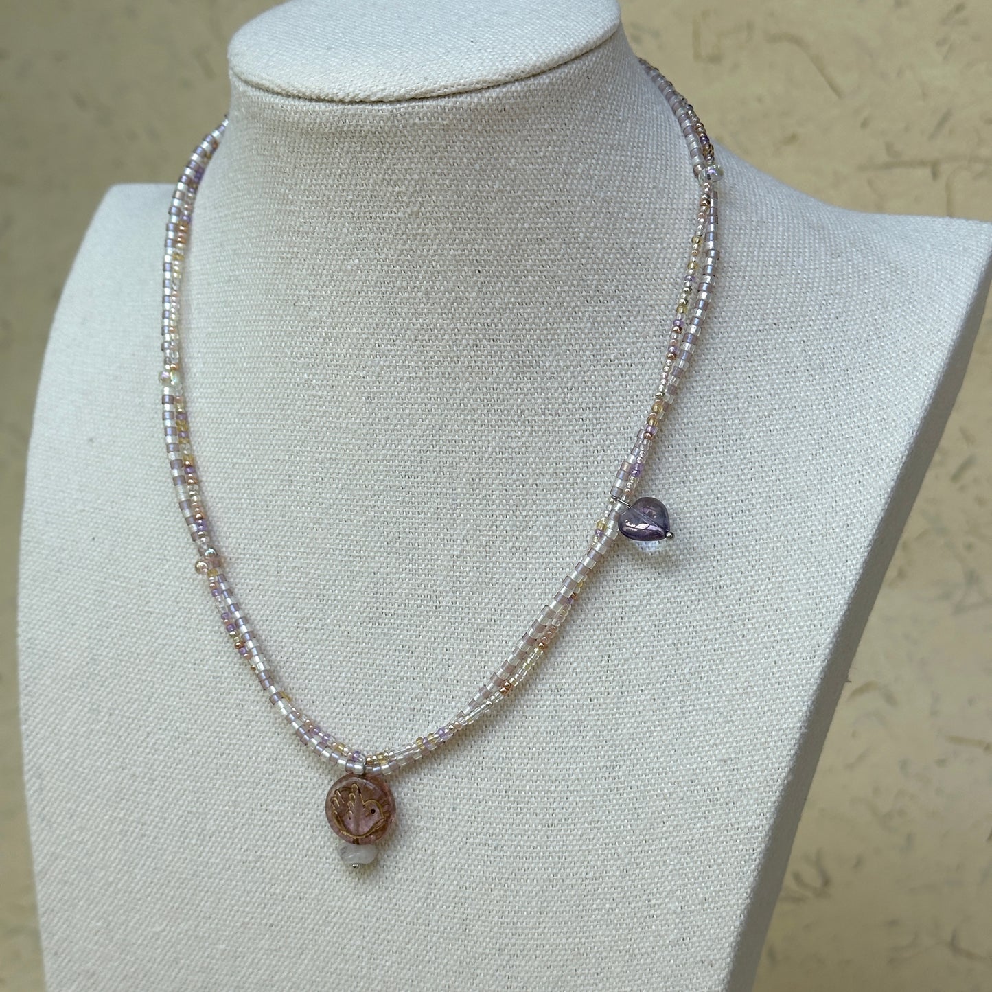 Iridescent Dew Necklace minimal styling on white fabric, emphasizing iridescent pastel glass beads and pendant detail