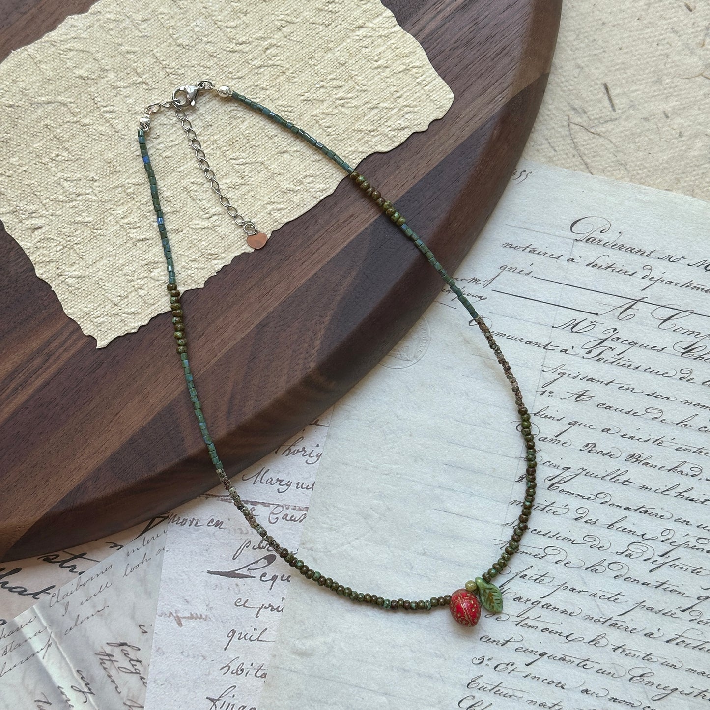 Close-up of red strawberry bead with tiny seeds and green leaf charm