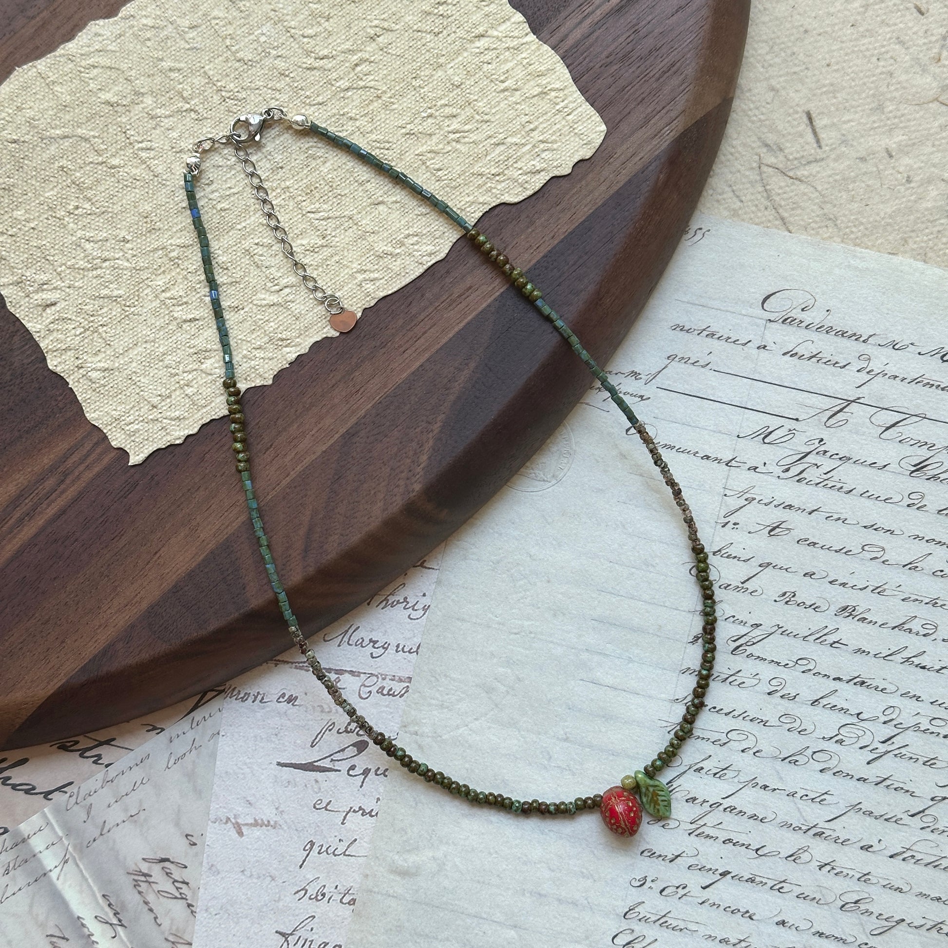 Close-up of red strawberry bead with tiny seeds and green leaf charm