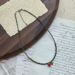 Close-up of red strawberry bead with tiny seeds and green leaf charm