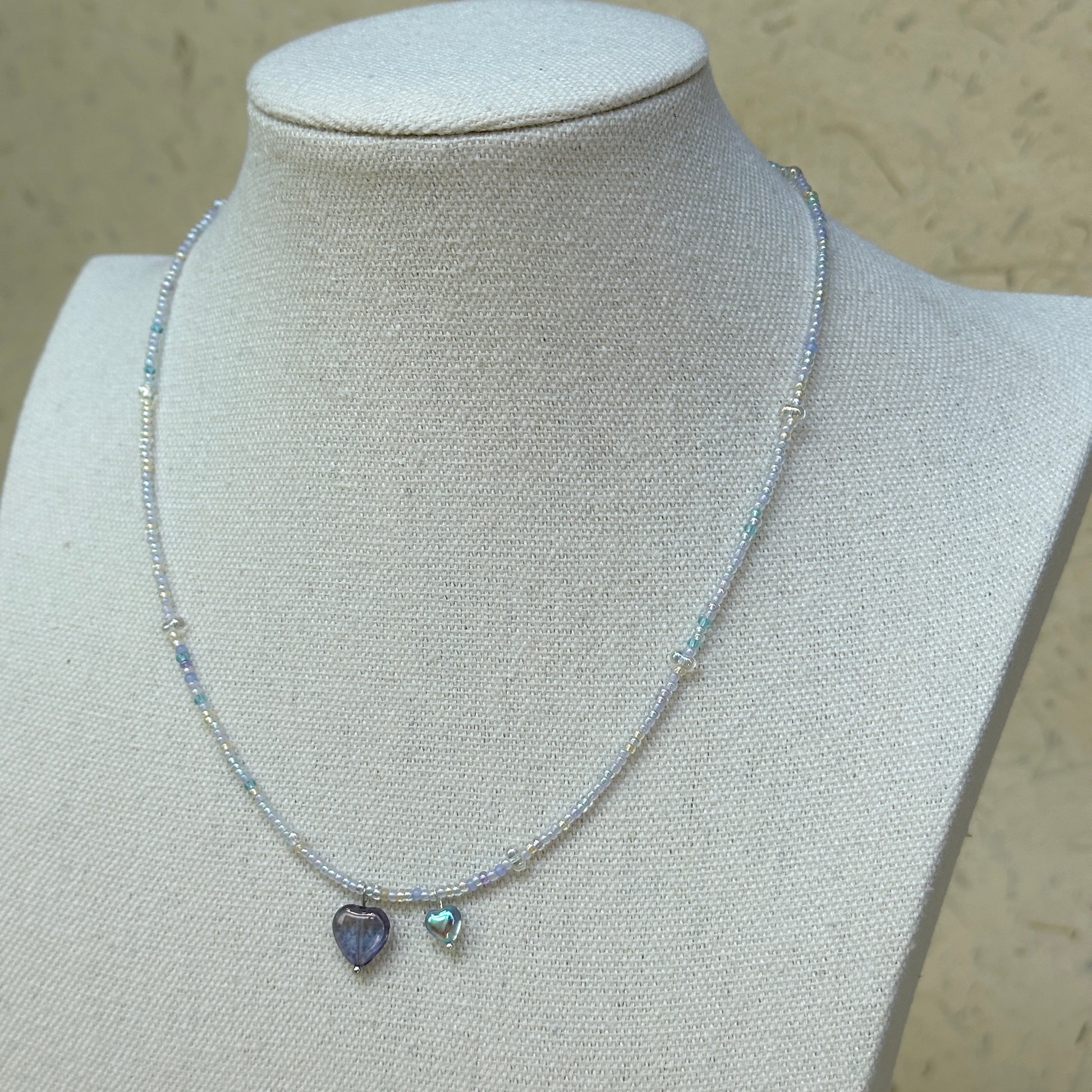 Celestial Love Necklace displayed on bust mannequin, emphasizing violet glass heart pendant and celestial blue accent