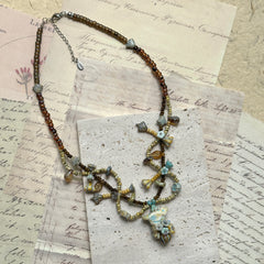 Vintage-inspired Autumn Whisper Necklace, handcrafted with amber glass, natural stones, and muted blue beads, lightweight cascading design flat display.