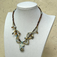 Autumn Whisper Necklace worn on white bust display, highlighting amber and blue bead details with leaf-shaped artisan accents.