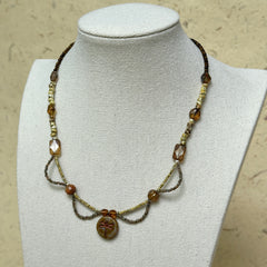 Dragonfly Whisper Necklace worn on white bust display, highlighting amber glass beads, earthy green stones, and the detailed dragonfly medallion centerpiece.