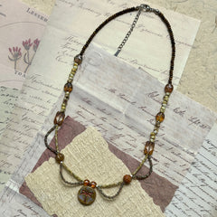 Vintage-inspired Dragonfly Whisper Necklace made of amber beads, Czech glass, and natural stones, lightweight cascading bead loops design shown flat.