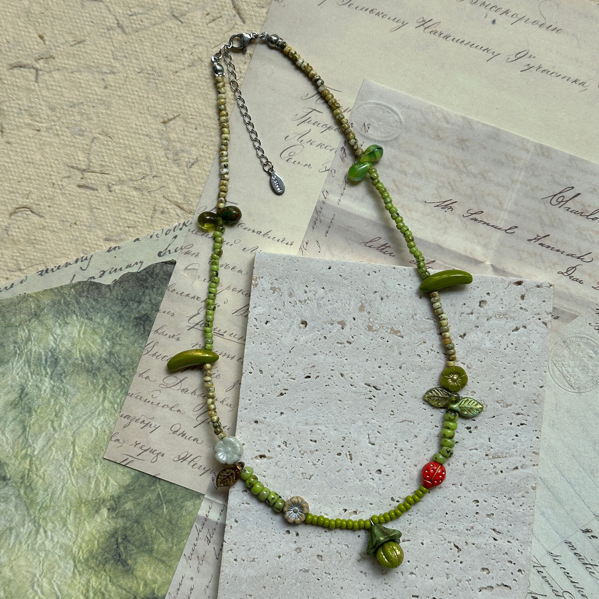 Fairy-tale inspired necklace with delicate green beads, tiny mushroom pendant, floral and berry accents, handcrafted in woodland theme.