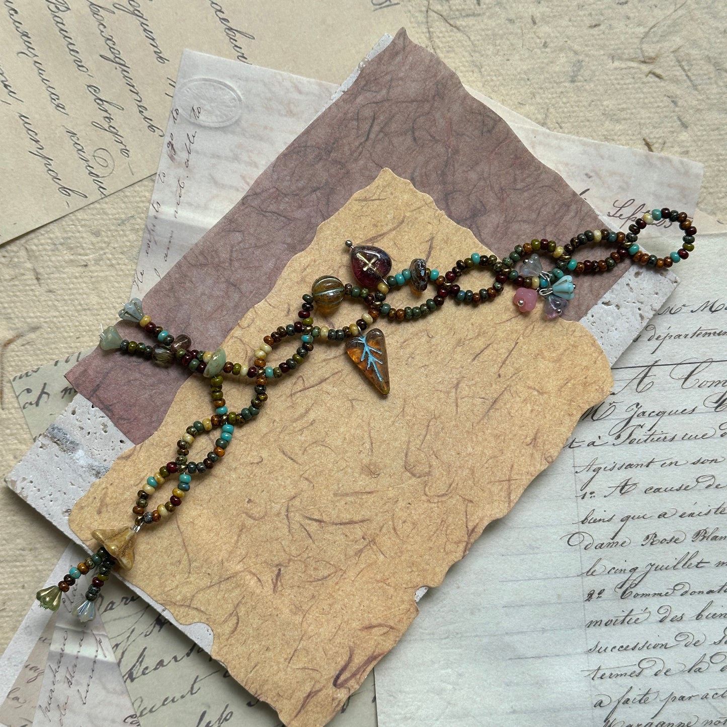 Harvest Charm Bracelet with warm autumn palette of amber and earthy hues, accented by whimsical charms, arranged in circular display on neutral background.