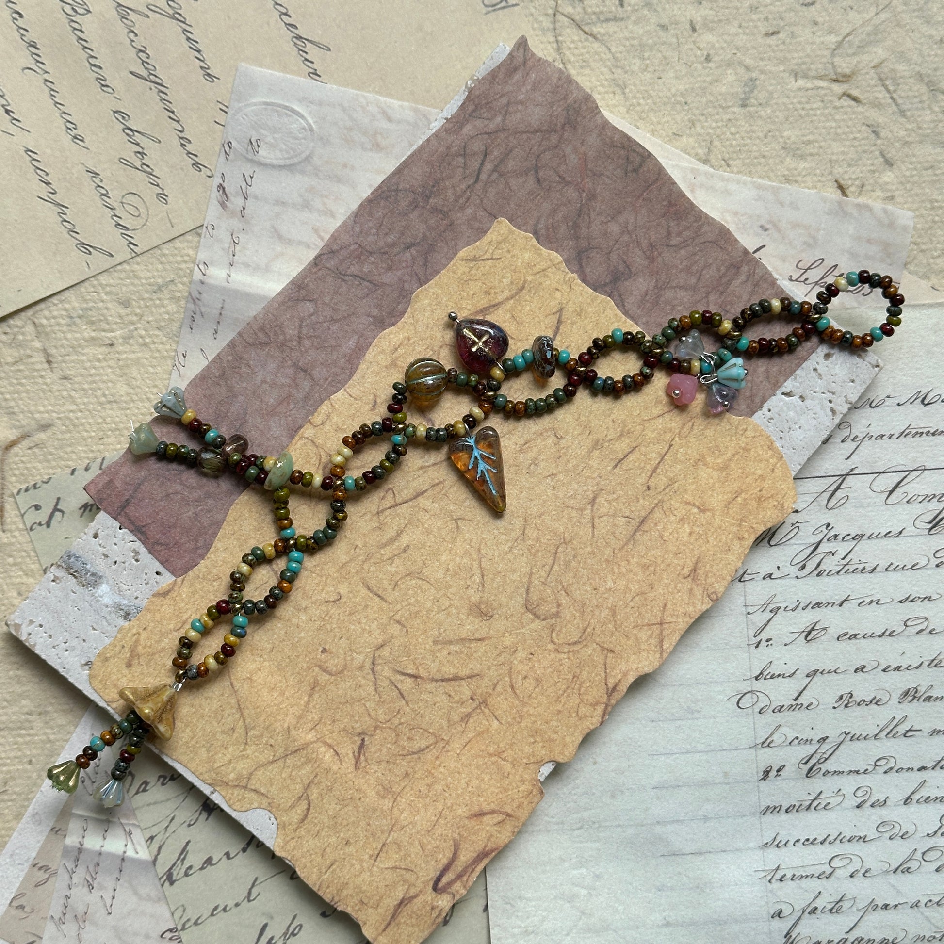 Harvest Charm Bracelet with warm autumn palette of amber and earthy hues, accented by whimsical charms, arranged in circular display on neutral background.