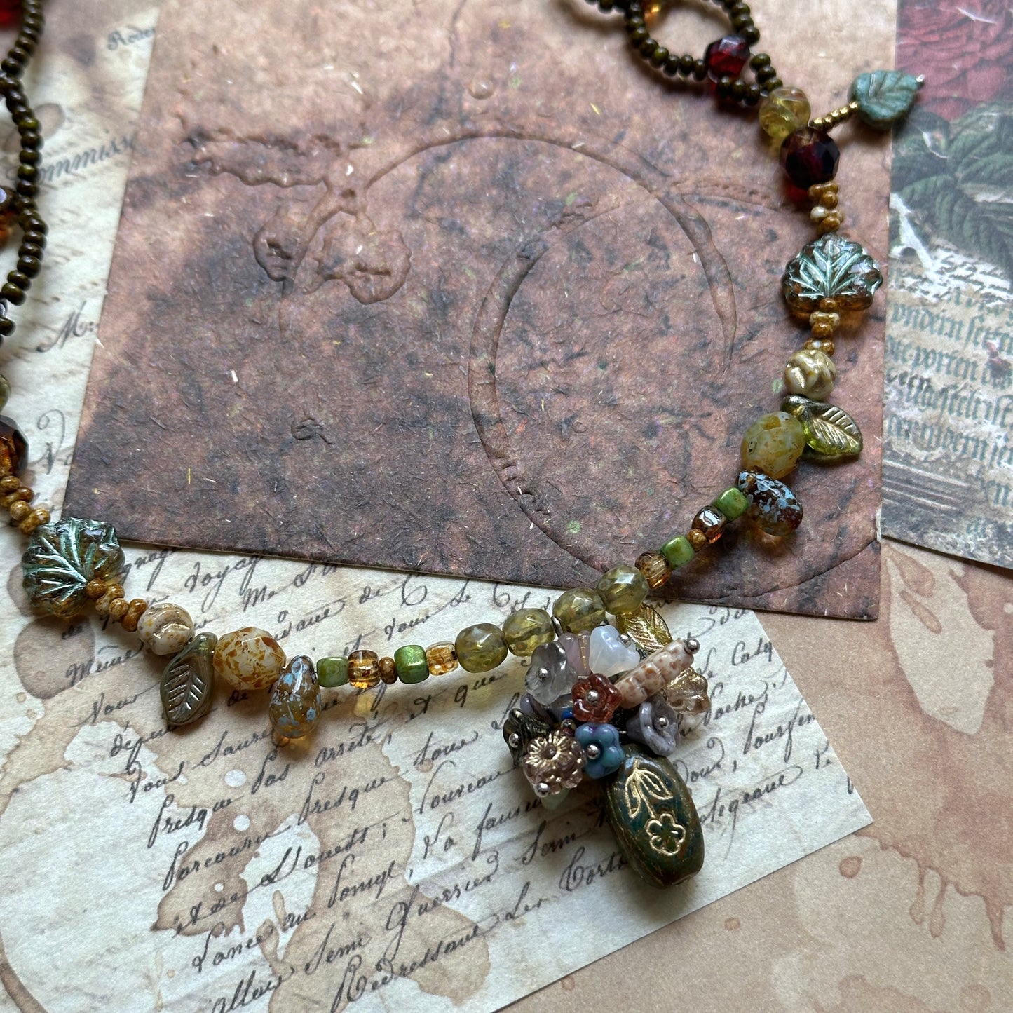 Woodland necklace with amphora (vase) charm and green leaf Czech beads on vintage paper background – Glazenya