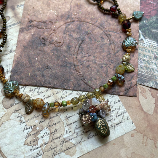 Woodland necklace with amphora (vase) charm and green leaf Czech beads on vintage paper background – Glazenya