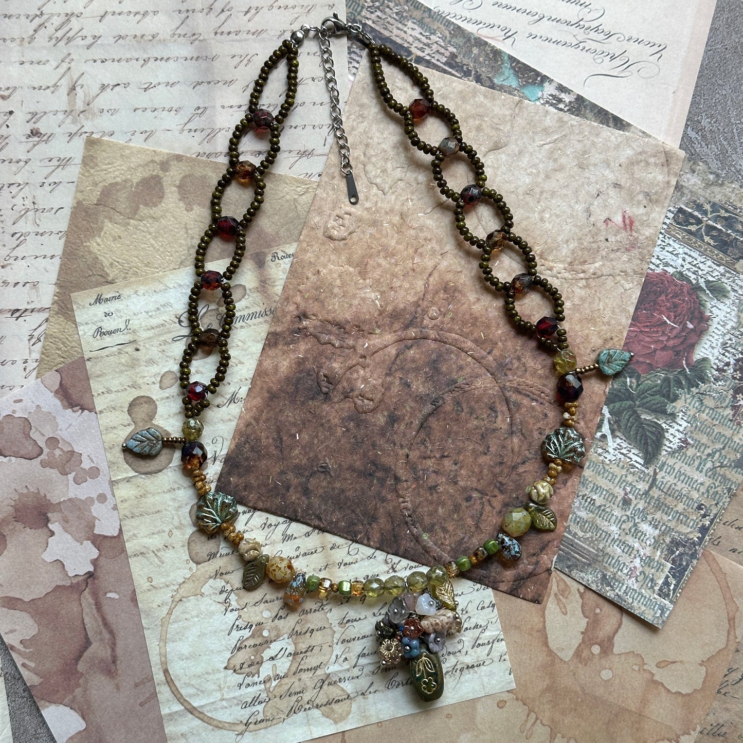Close-up of olive-green amphora glass pendant with gold motif