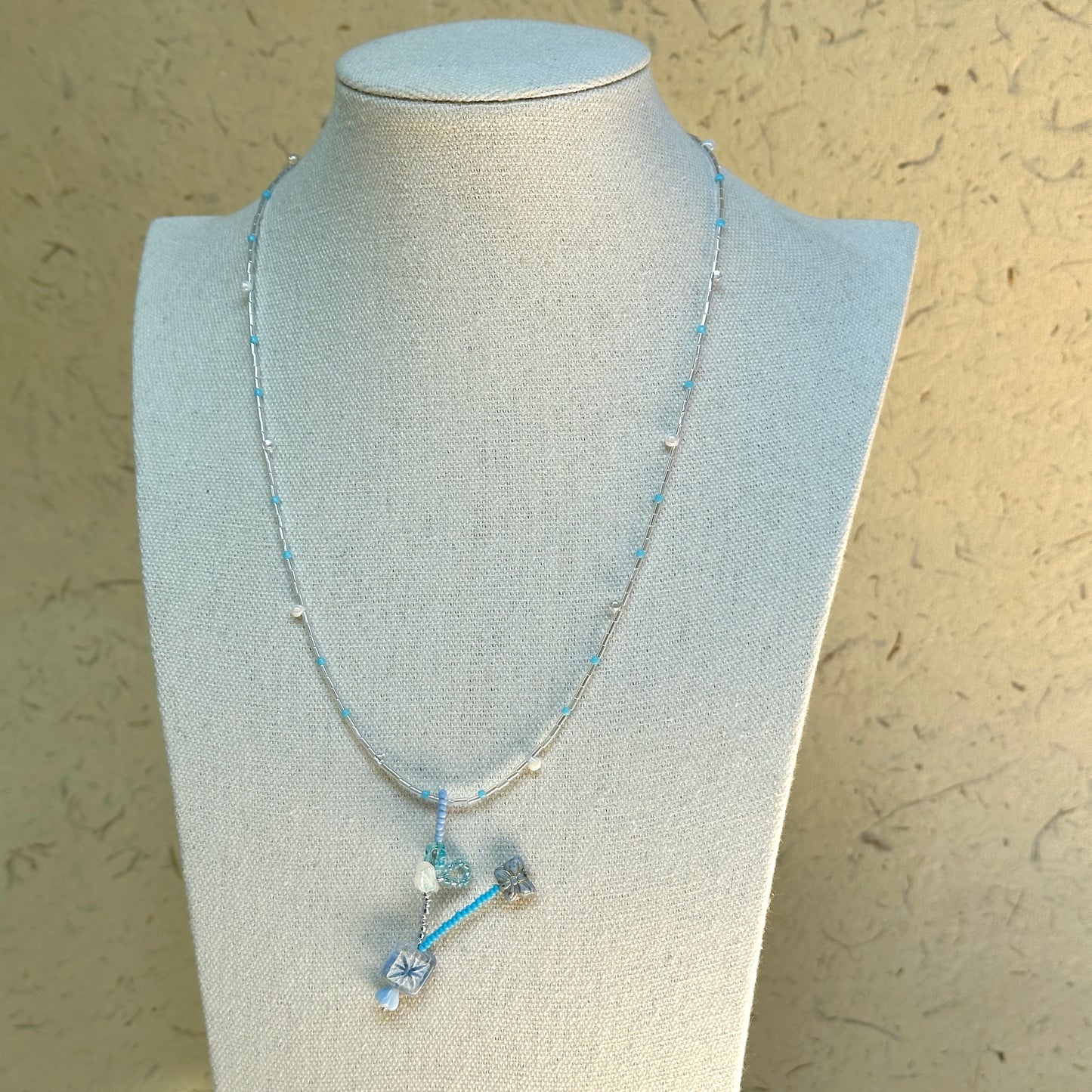 Frosted Sky Necklace on mannequin—sky-blue beads with frosted glass flowers and crystal drops; elegant and easy to wear.