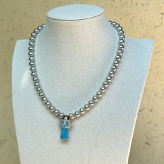 Angel’s Grace Necklace on mannequin—classic faux-pearl strand with sky-blue angel charm; graceful and easy to wear.