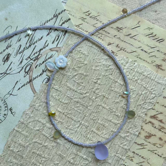 Close detail of Lilac Dew Necklace—lavender seed beads with a frosted lilac glass teardrop pendant; delicate and lightweight.