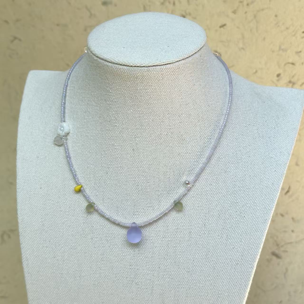 Lilac Dew Necklace on mannequin—delicate lavender strand with frosted lilac teardrop pendant; airy and easy to wear.