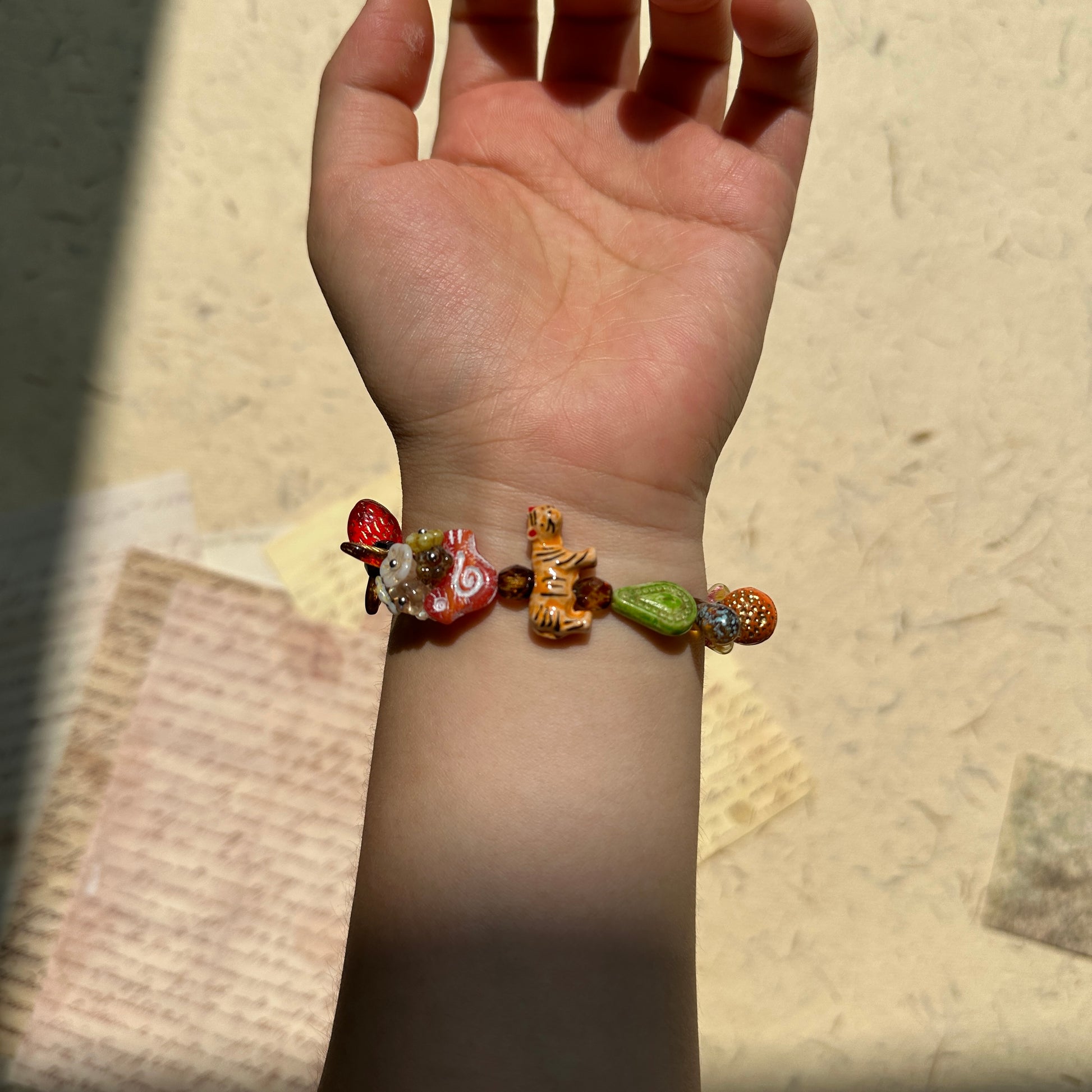 Glazenya Tiger Orchard Bracelet worn on wrist, colorful fruit and tiger glass beads shimmering under natural light, evoking harvest season joy