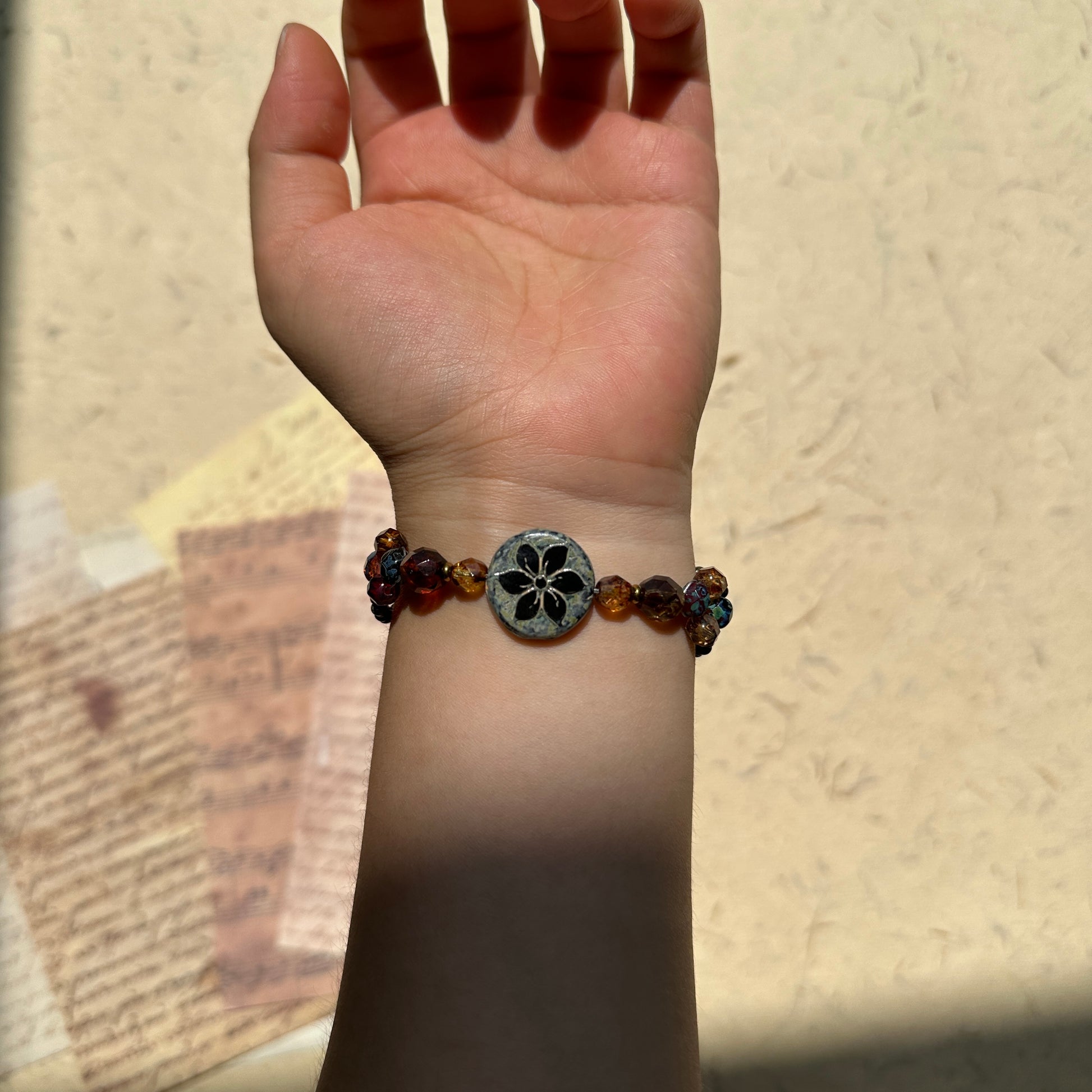 Antique Flower Window Bracelet worn on wrist, warm amber and garnet tones with bronze accents, refined handcrafted silhouette