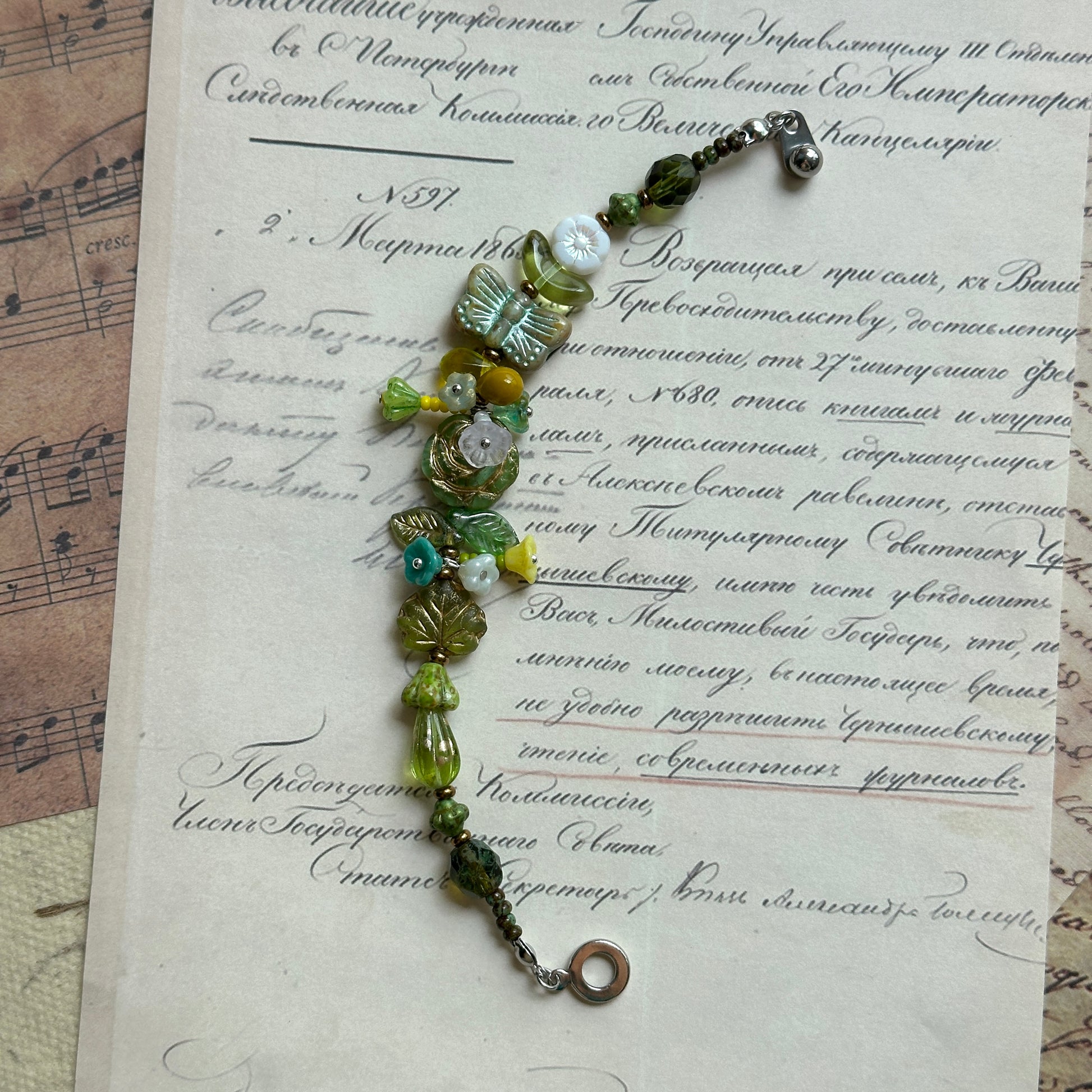 Artisan bracelet with butterfly, bell-shaped flowers, and glass accents