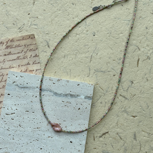 Morning Dew Petal Necklace flat-lay on vintage script paper, pastel seed beads in soft green and blush with a single pink floral focal