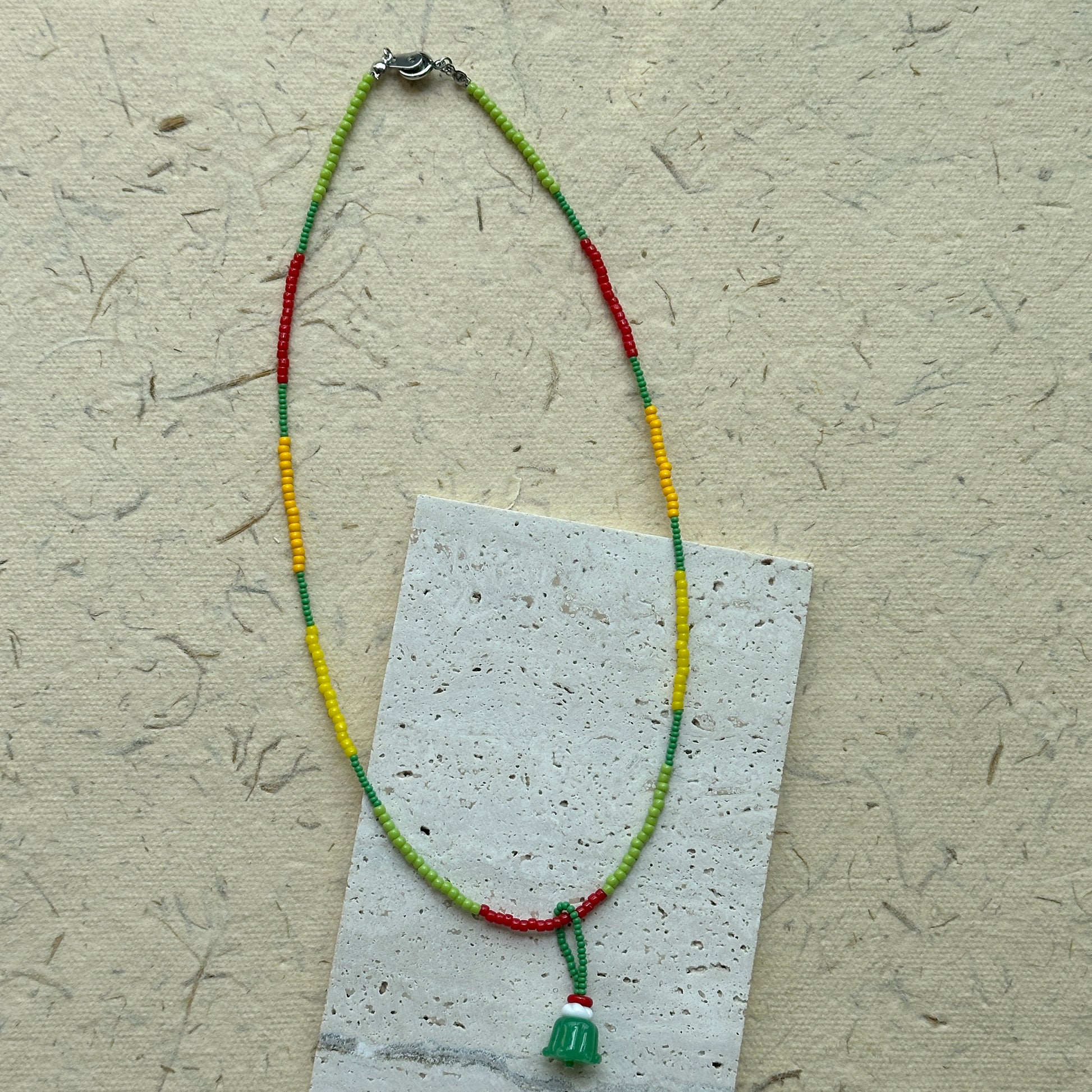 Close-up of green jelly-cake style pendant with red accent loop
