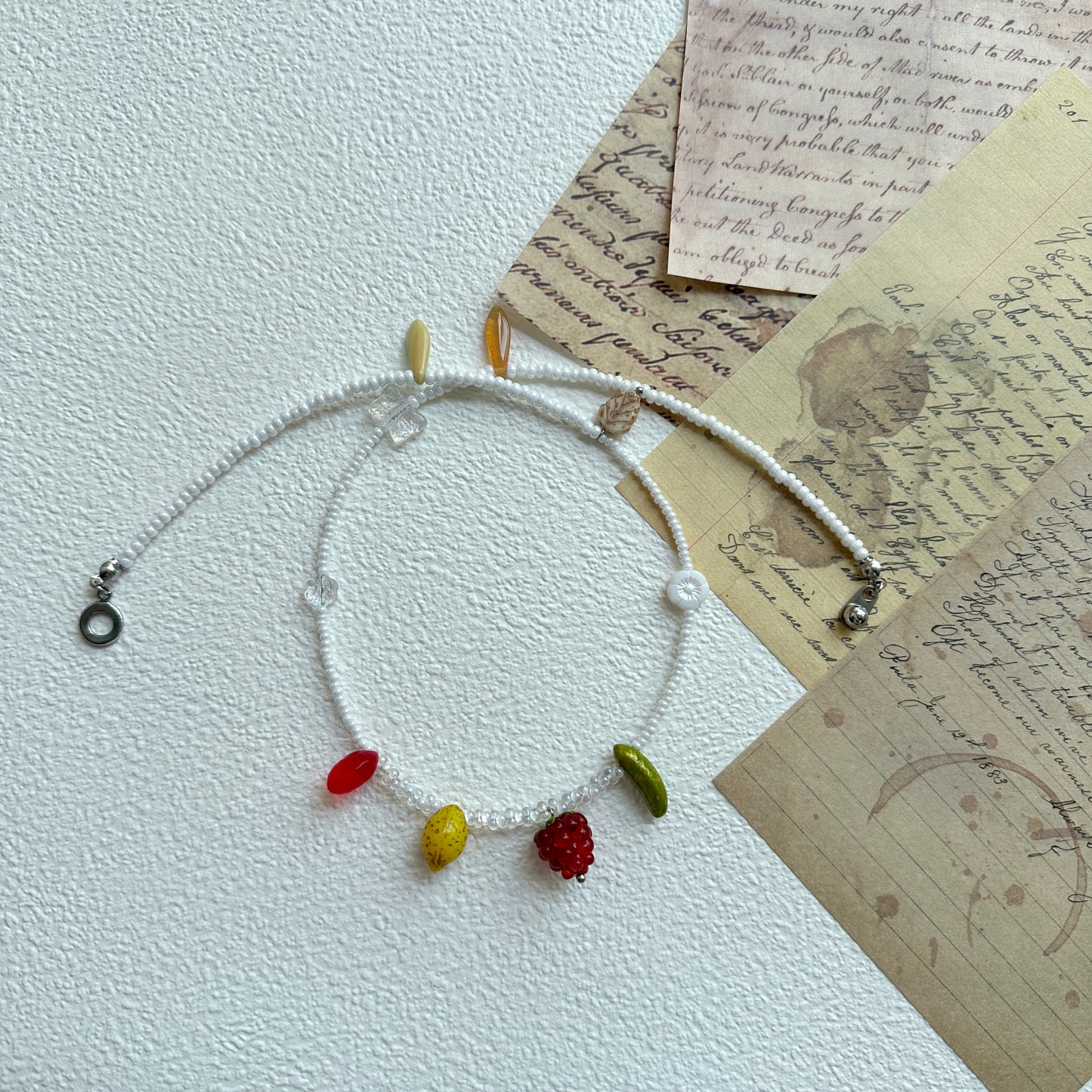 Close-up of red berry glass charm and green bead on necklace