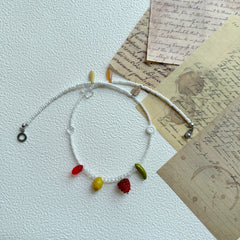 Close-up of red berry glass charm and green bead on necklace