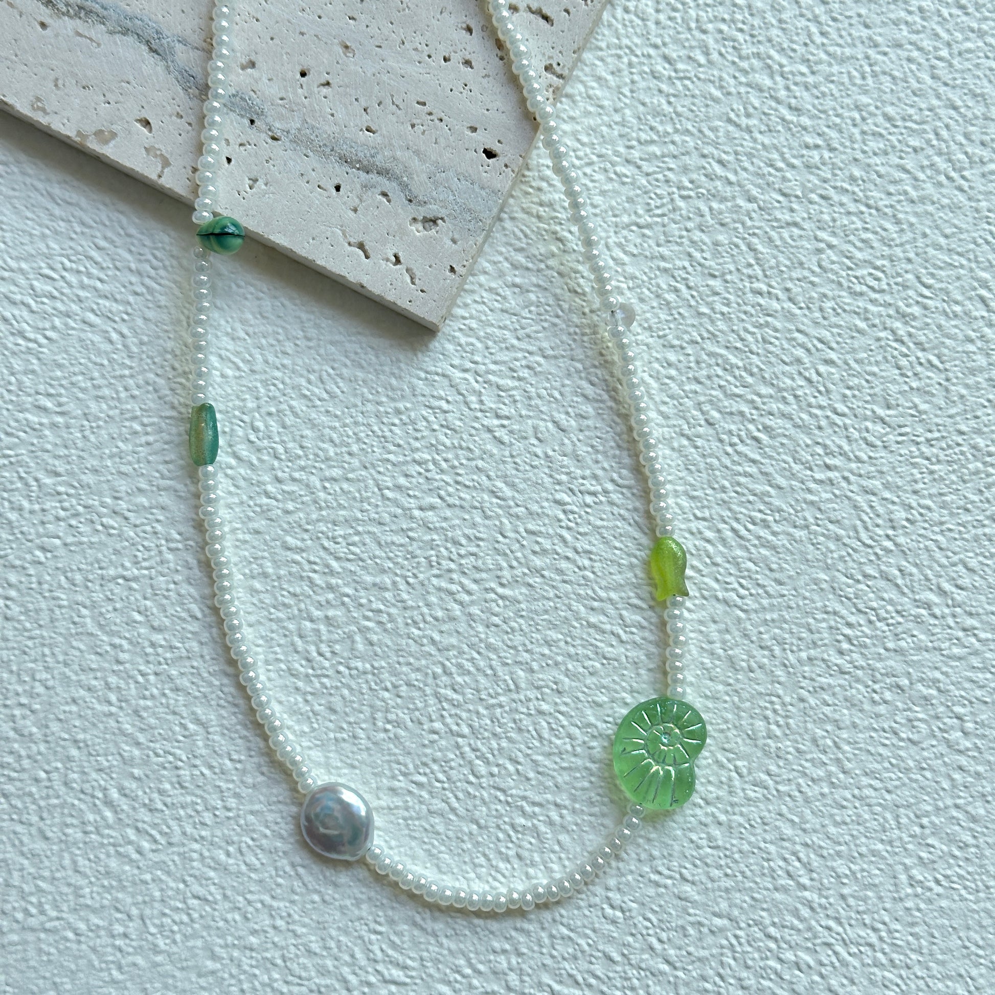 Lily Pond Necklace with green leaf bead and pearl-like accent on display bust