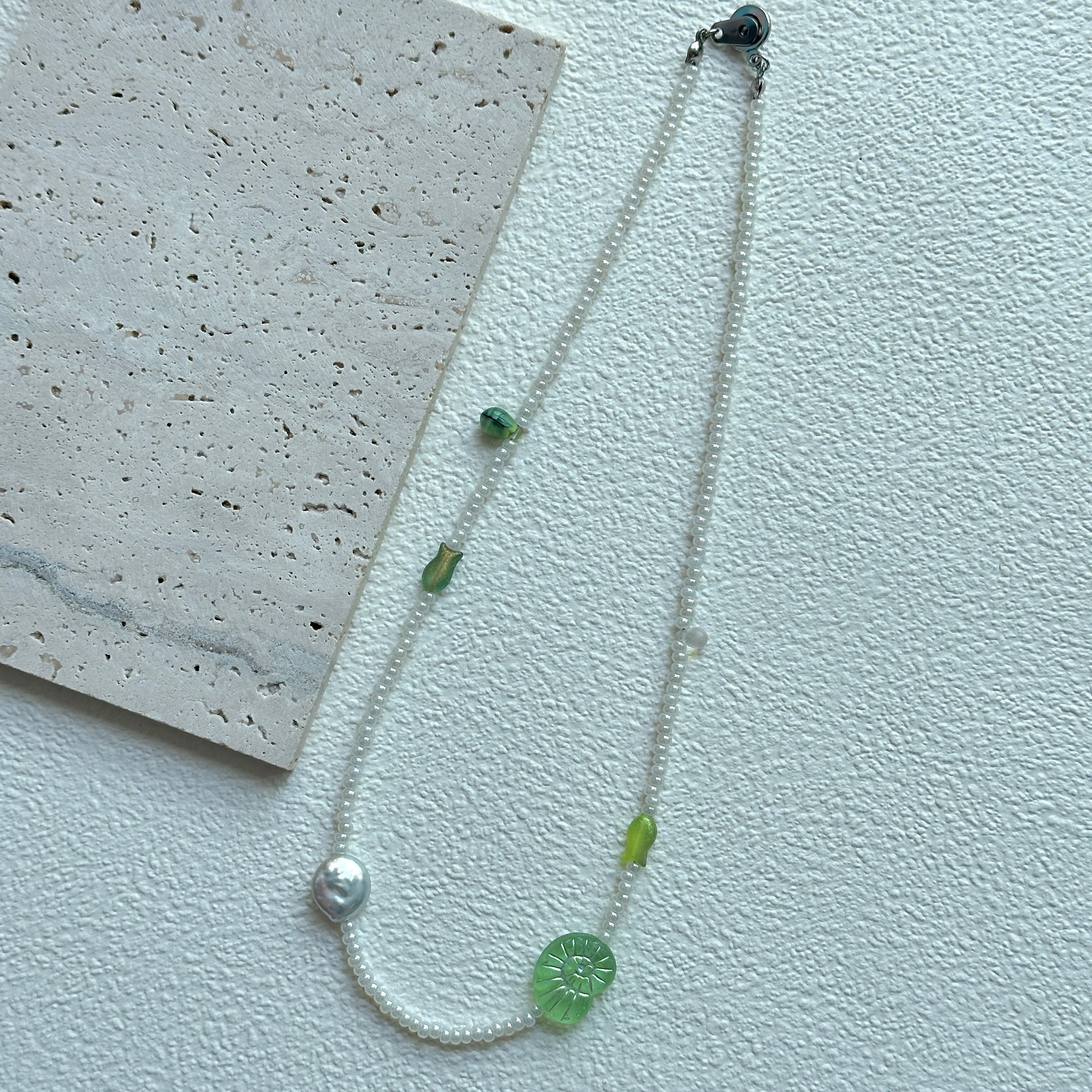 Close-up of green leaf focal bead with white seed beads on necklace