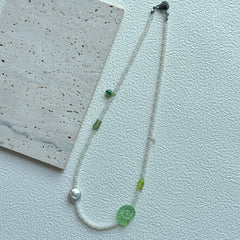 Close-up of green leaf focal bead with white seed beads on necklace