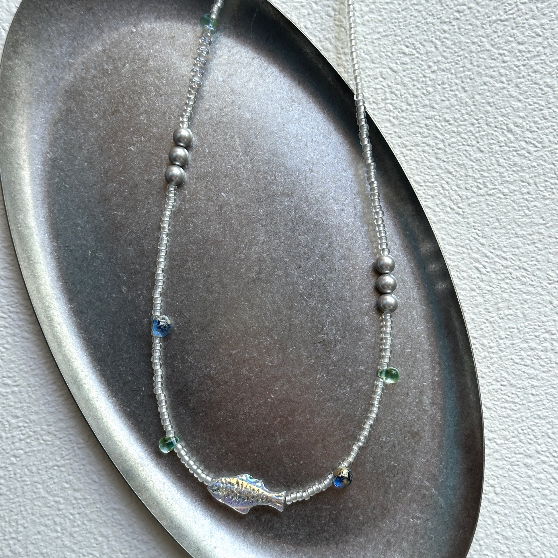 Full view of Azure Fish Necklace arranged on stone background