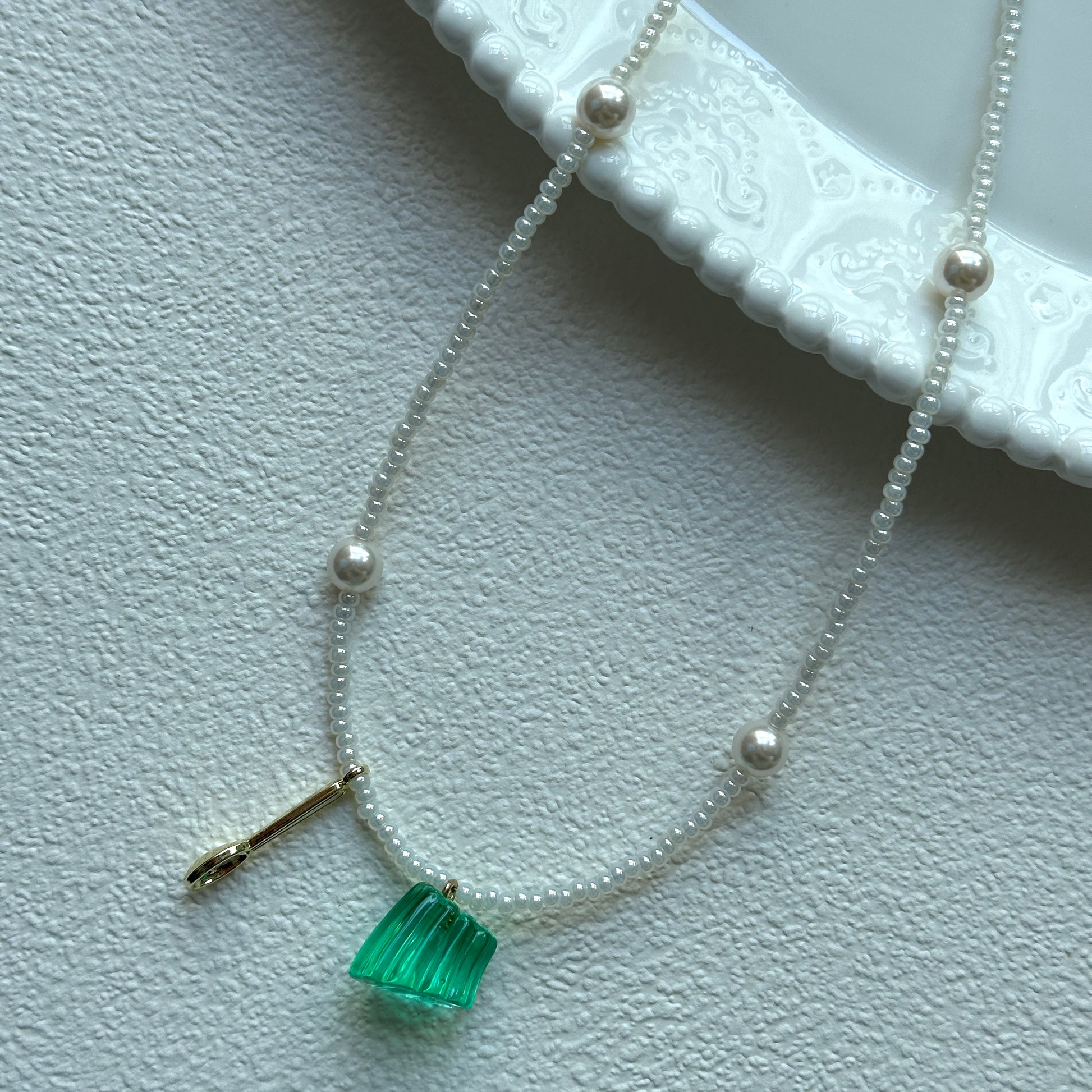 Aurora Green Necklace with green pendant and pearl accents on display bust