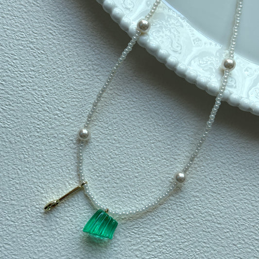 Aurora Green Necklace with green pendant and pearl accents on display bust