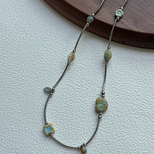 Rustic Sunburst Necklace with sunburst and floral motif beads on display bust