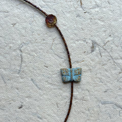 Close-up of butterfly-shaped focal bead with earthy brown seed beads