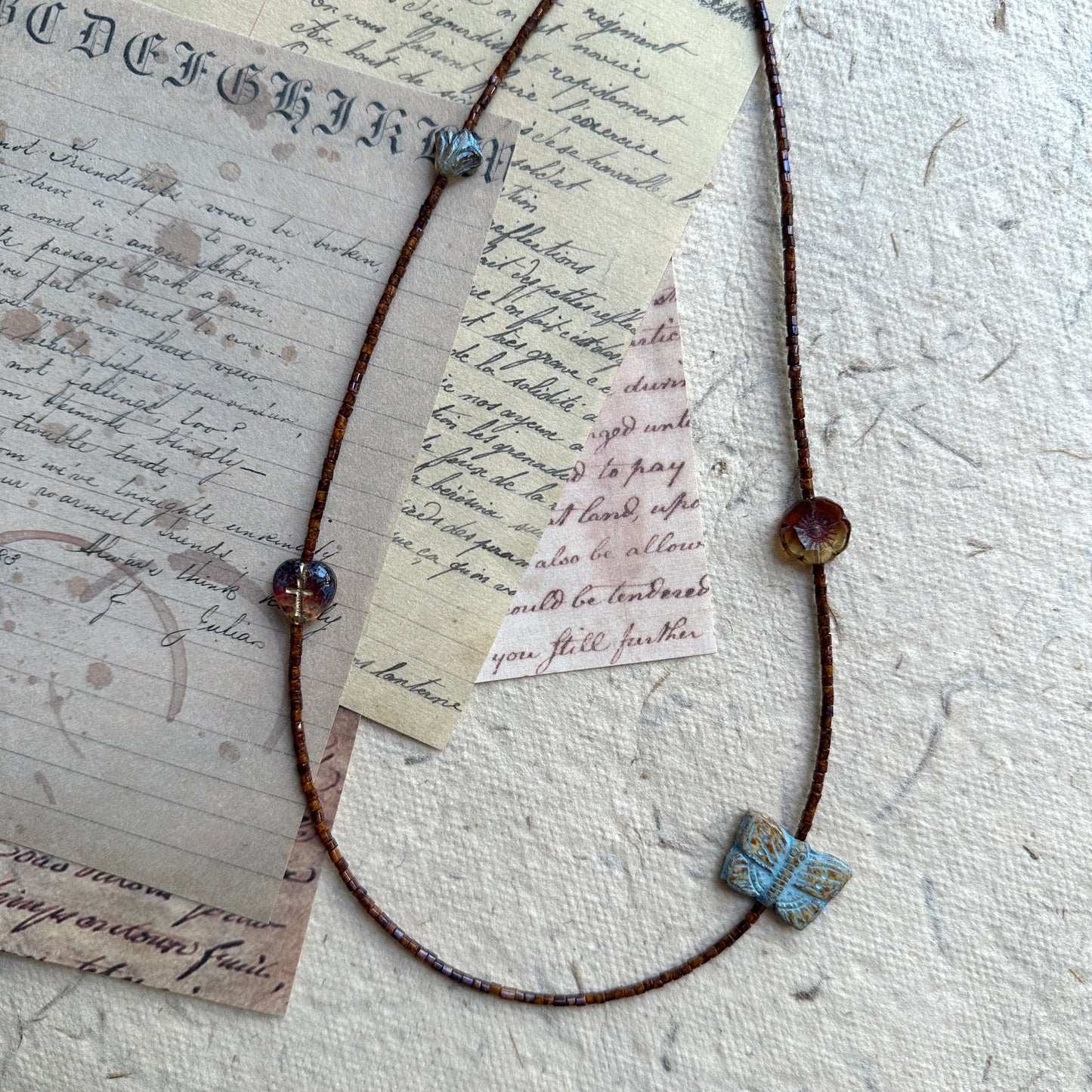 Full view of Rustic Butterfly Necklace displayed on beige stand