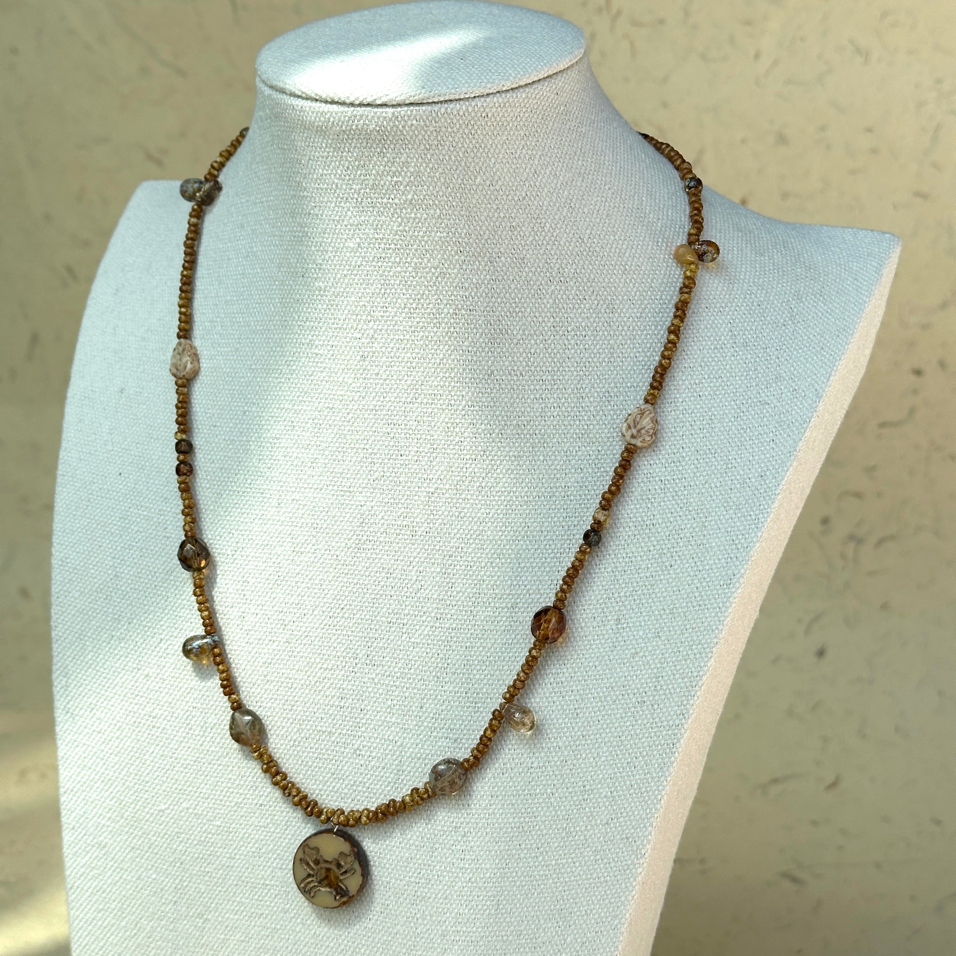 Rustic brown seed bead strand with zodiac-inspired design