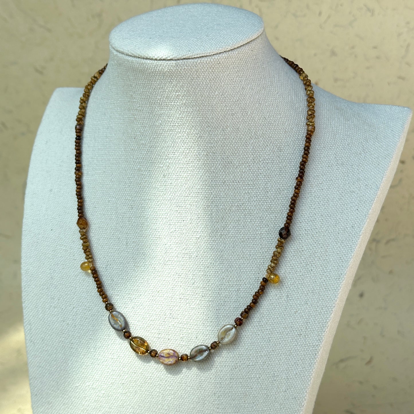 Full view of Sunset Relic Necklace displayed on beige stand