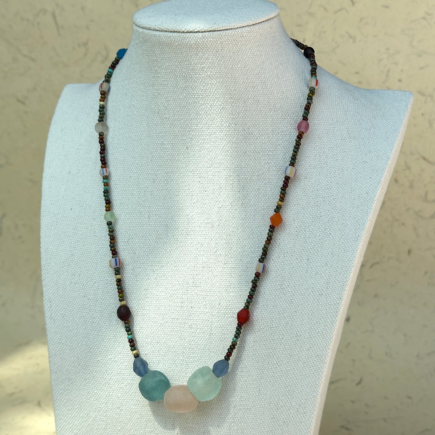 Full view of Wanderlust Stone Necklace laid beside vintage paper props