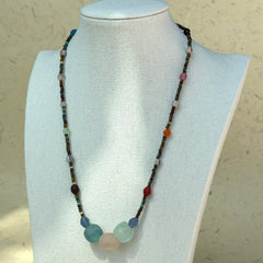 Full view of Wanderlust Stone Necklace laid beside vintage paper props