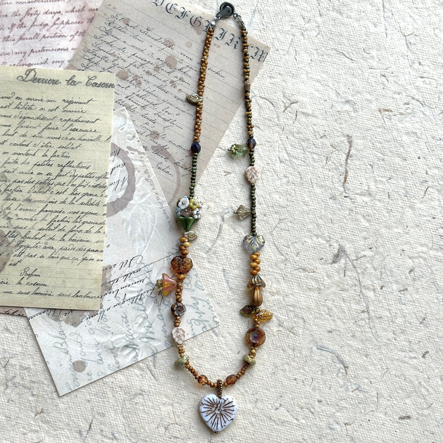 Close-up of white heart pendant with etched leaf vein details