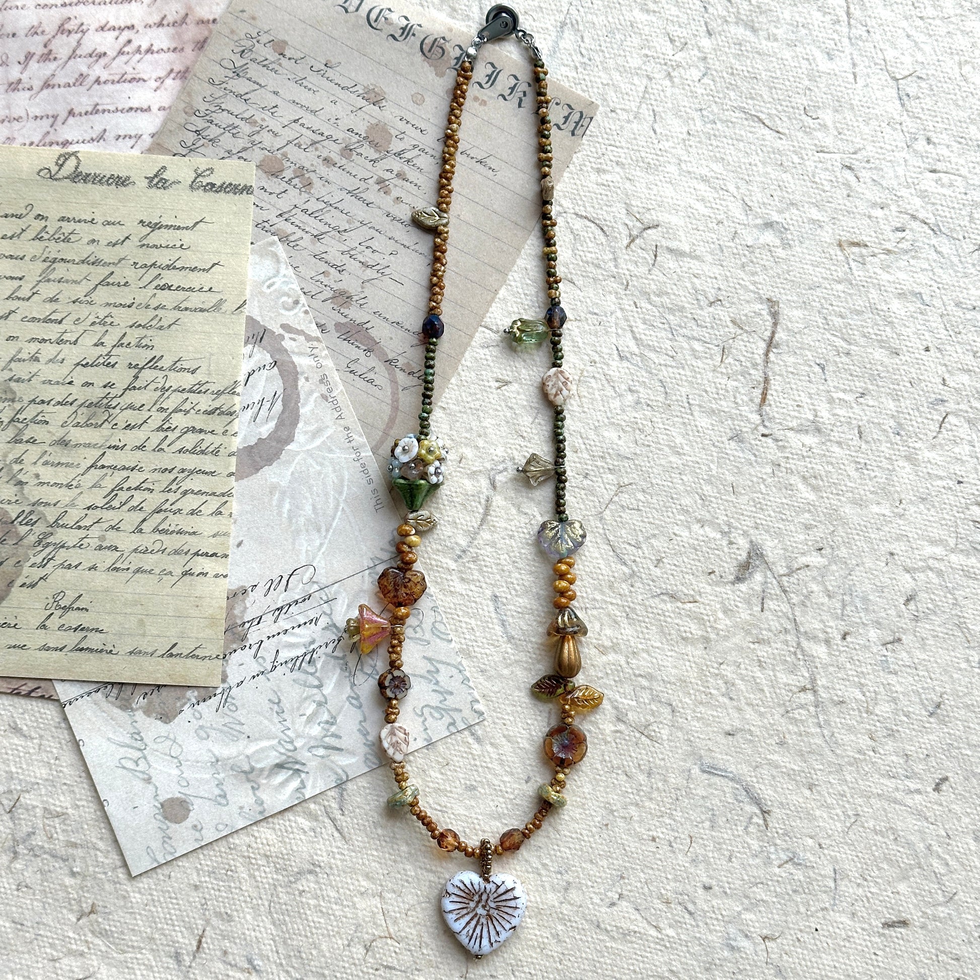 Close-up of white heart pendant with etched leaf vein details