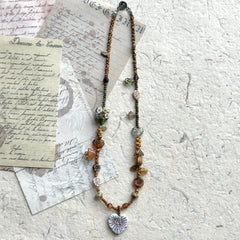 Close-up of white heart pendant with etched leaf vein details